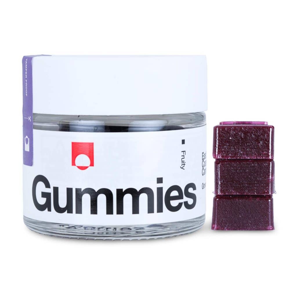 A clear jar with a white lid labeled "Gummies" containing purple gummies, with four stacked purple gummies next to it.