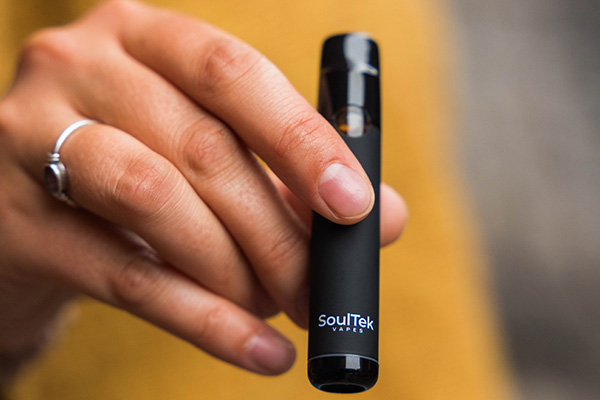 a woman holding a disposable cannabis vape pen.